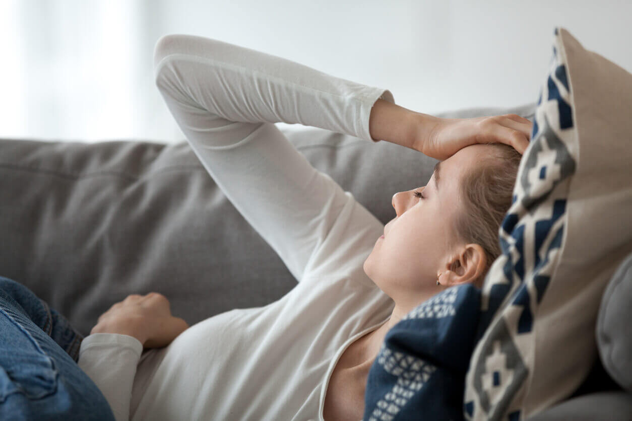 woman laying on her sofa with a headache